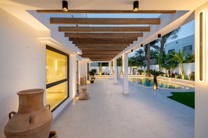 Covered pergola walkway leading to the renovated pool, evening lighting — The Meadows villa after renovation