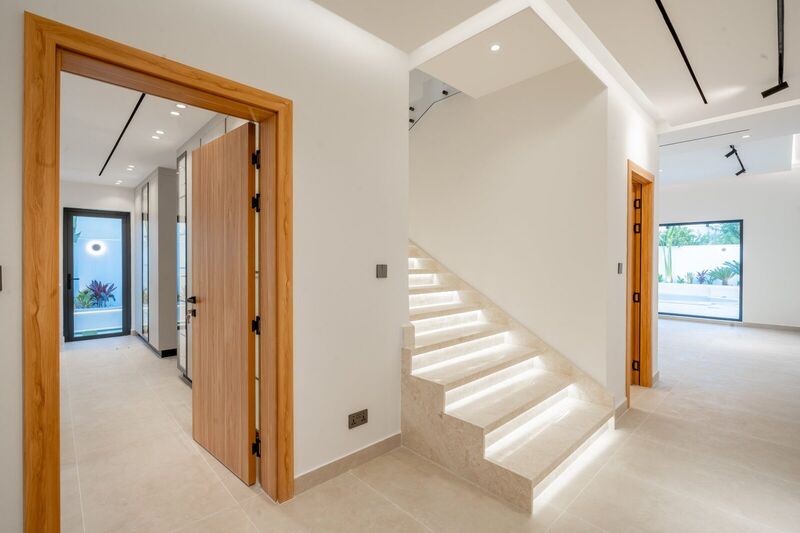 New open-riser staircase with stone treads and glass balustrade in the entrance hall — The Meadows villa