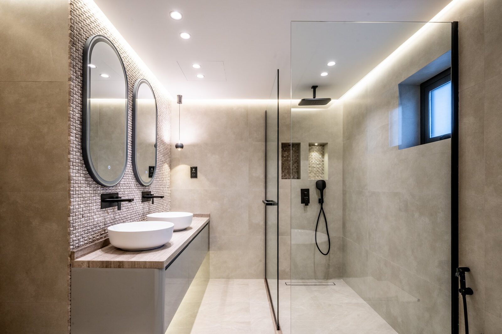 Family bathroom after renovation — large-format stone tiling and double-basin vanity