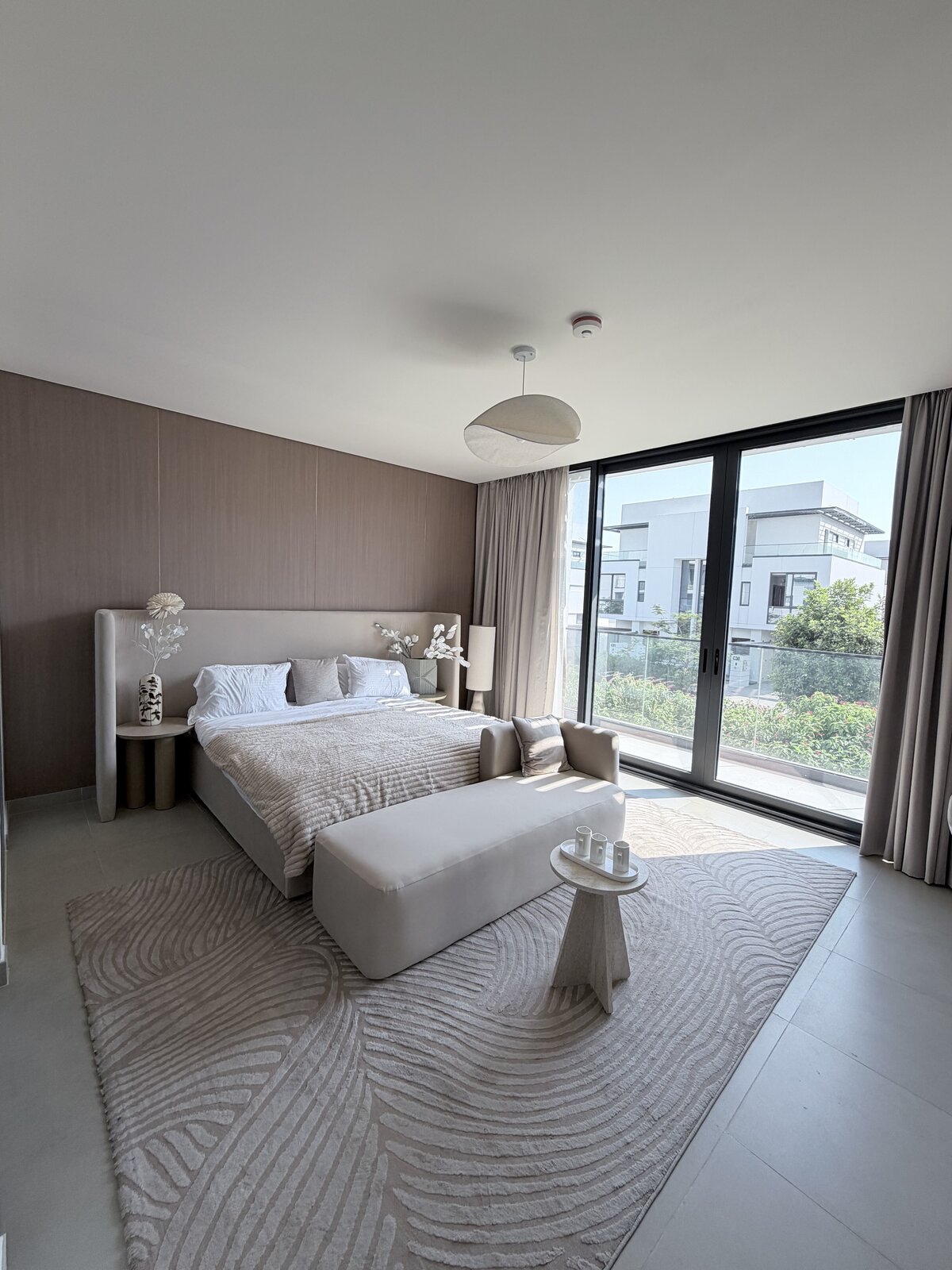 Palm Jumeirah townhouse primary bedroom after renovation — upholstered bed, rug and terrace access, fully furnished