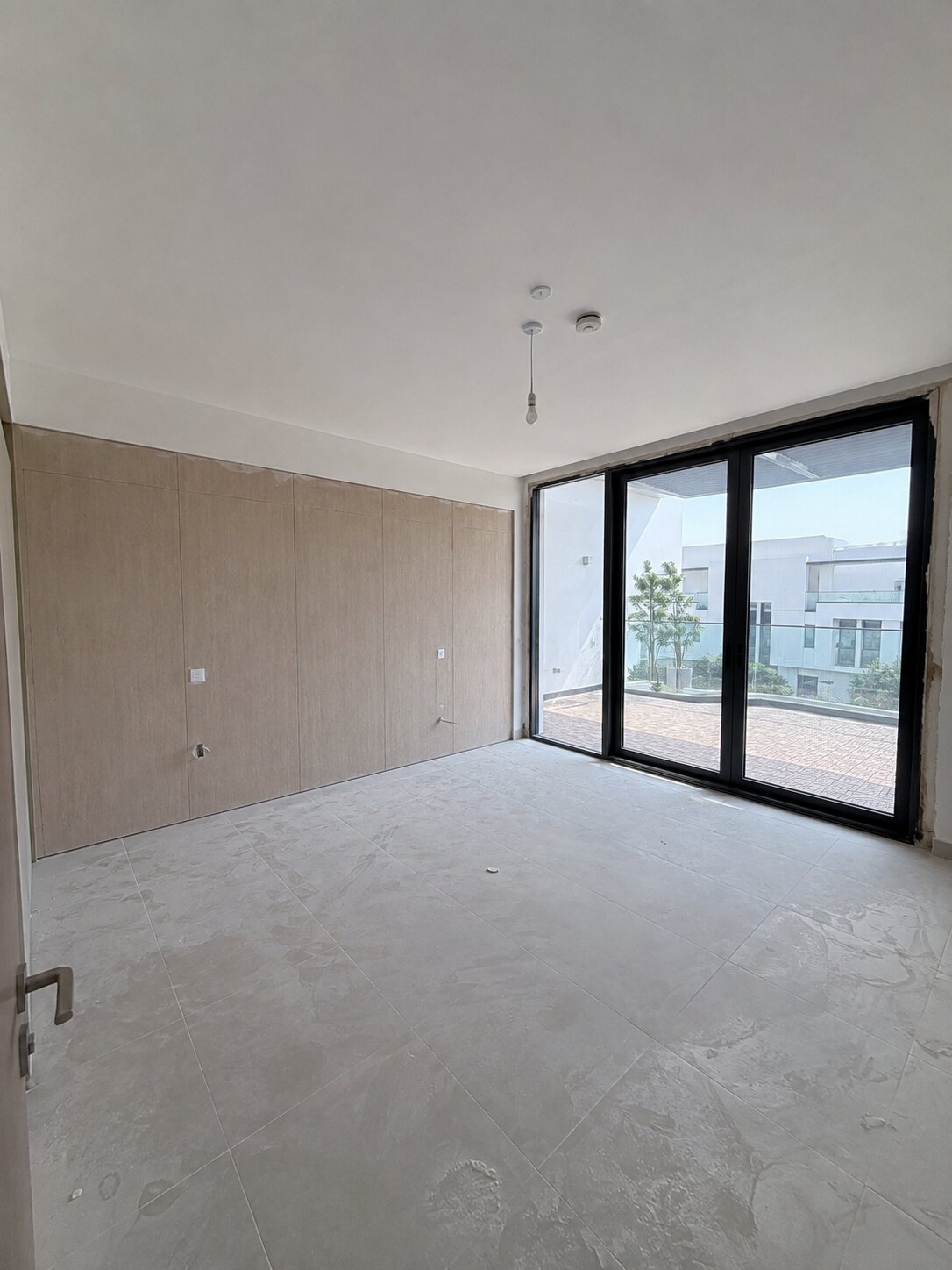 Palm Jumeirah townhouse primary bedroom before renovation — empty room with wardrobe panelling and bare terrace door