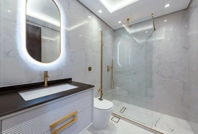 Arabian Ranches villa ensuite after renovation — marble finish with backlit mirror and glass walk-in shower