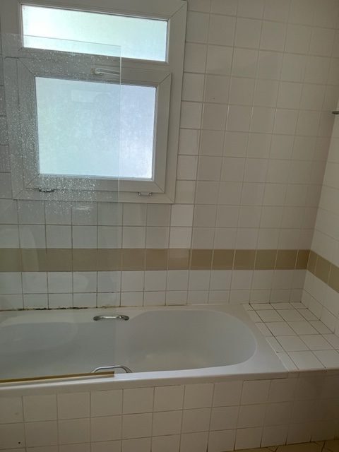 Master ensuite bathroom before renovation — original dated tiling and tub
