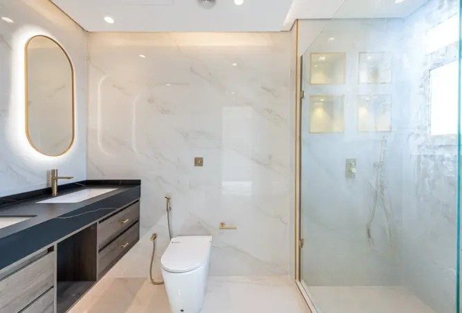 Master ensuite bathroom after renovation — book-matched marble walls and frameless walk-in shower